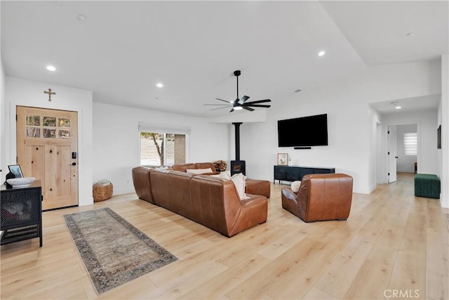 living room with ceiling fan, light hardwood / wood-style flooring, and a wood stove