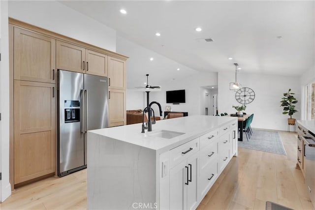 kitchen with pendant lighting, light brown cabinetry, sink, high end refrigerator, and a kitchen island with sink