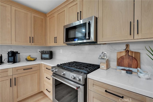 kitchen with tasteful backsplash, appliances with stainless steel finishes, and light brown cabinetry