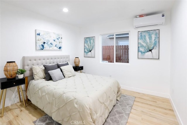 bedroom featuring light hardwood / wood-style floors and a wall unit AC