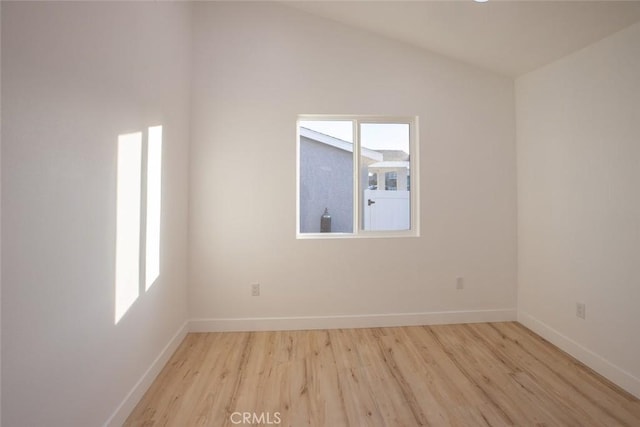 empty room featuring lofted ceiling, a wealth of natural light, and light hardwood / wood-style flooring