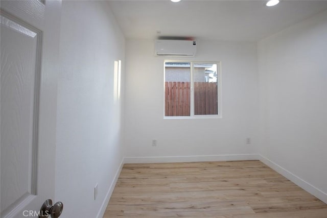 empty room with light hardwood / wood-style flooring and an AC wall unit