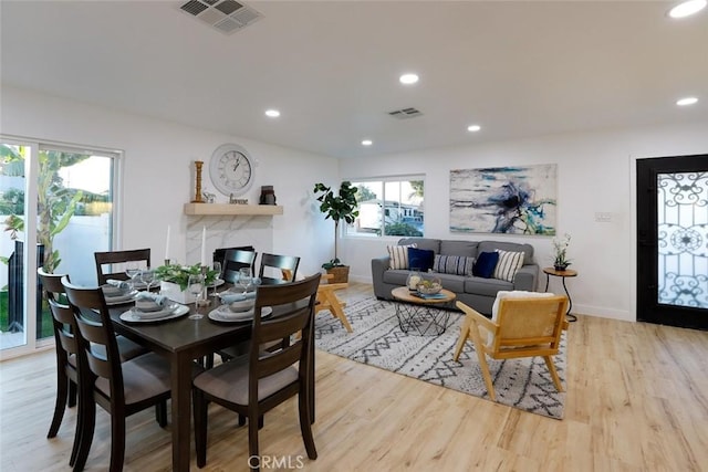 dining room featuring a high end fireplace and light hardwood / wood-style floors