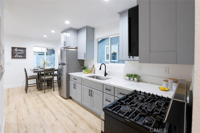 kitchen featuring sink, gray cabinetry, range with gas stovetop, and stainless steel refrigerator