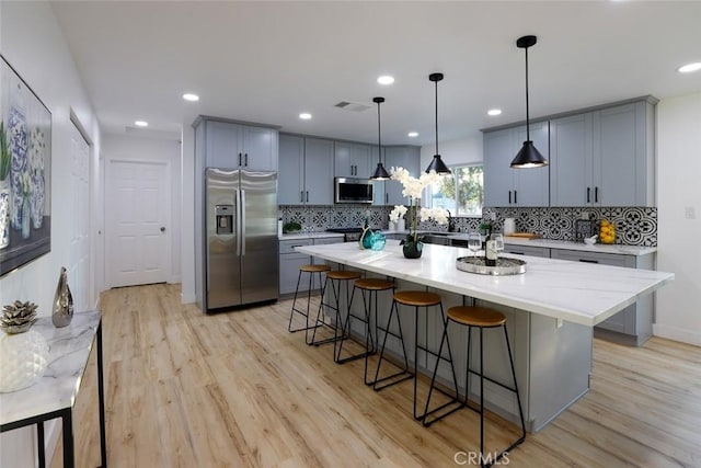 kitchen featuring pendant lighting, light wood-type flooring, a center island, and appliances with stainless steel finishes