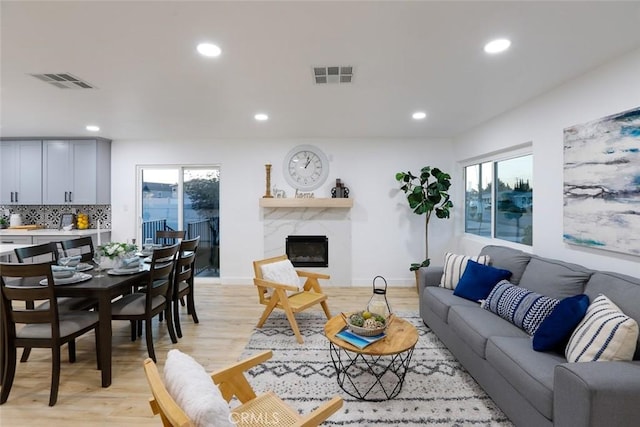 living room featuring a wealth of natural light, a fireplace, and light wood-type flooring