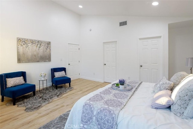 bedroom featuring high vaulted ceiling and light hardwood / wood-style floors