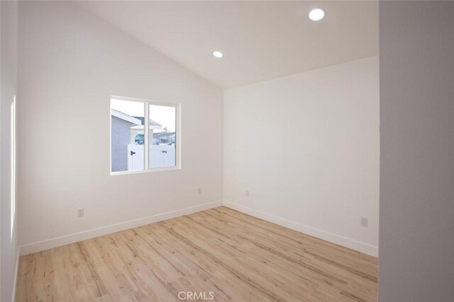 empty room with vaulted ceiling and light hardwood / wood-style flooring