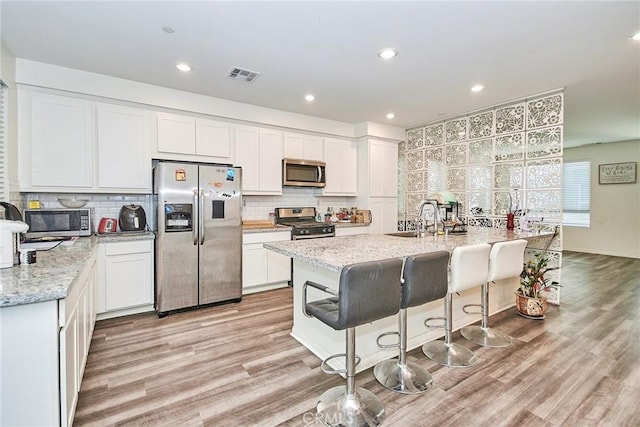 kitchen with light stone counters, stainless steel appliances, and white cabinets