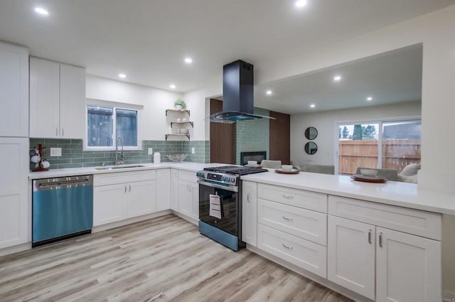 kitchen featuring stainless steel appliances, island exhaust hood, sink, and white cabinetry