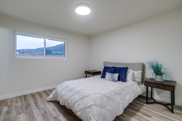 bedroom with a mountain view and light hardwood / wood-style floors