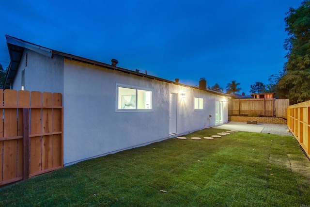 back house at dusk featuring a yard