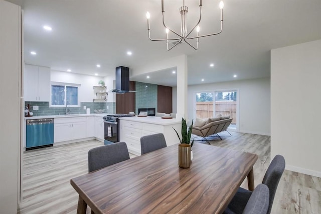 dining room with an inviting chandelier, sink, and light hardwood / wood-style flooring