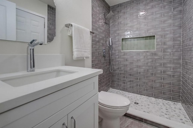 bathroom with vanity, toilet, and a tile shower