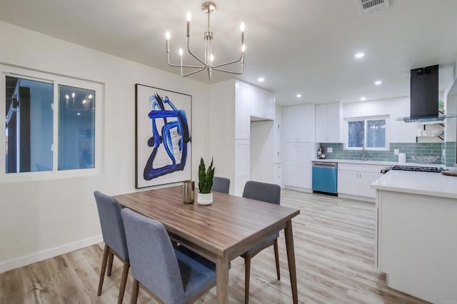 dining room with sink, a notable chandelier, and light wood-type flooring