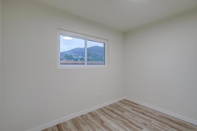 empty room featuring a mountain view and light hardwood / wood-style floors