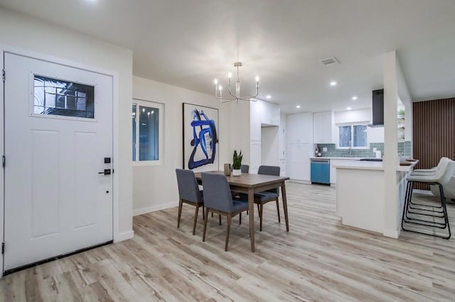 dining space featuring sink, a chandelier, and light wood-type flooring