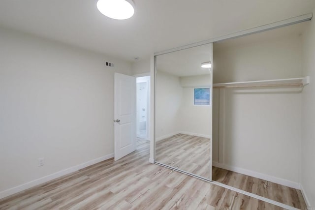 unfurnished bedroom with a closet and light wood-type flooring