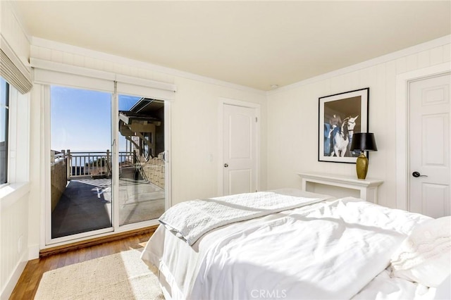 bedroom with access to exterior, ornamental molding, and wood finished floors