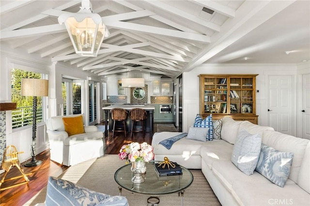 living area featuring lofted ceiling with beams, a decorative wall, wood finished floors, and visible vents