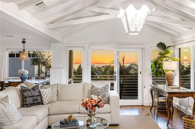 sunroom / solarium featuring beamed ceiling, a wealth of natural light, and a chandelier