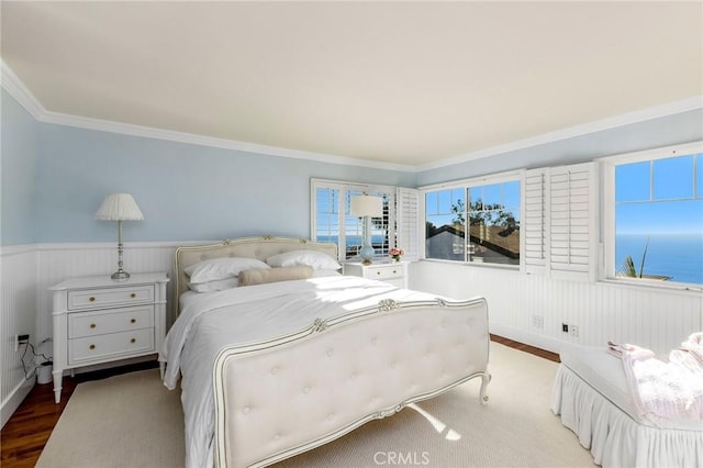 bedroom featuring ornamental molding, wood finished floors, and wainscoting