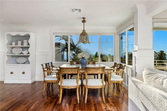 dining room with a decorative wall, dark wood finished floors, ornamental molding, visible vents, and wainscoting