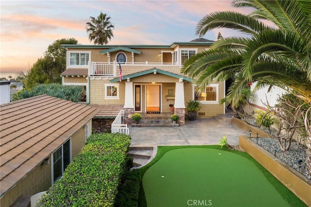 view of front of property with a patio, a balcony, and fence