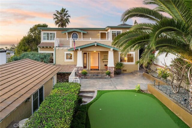 view of front of home with fence, a patio, and a balcony