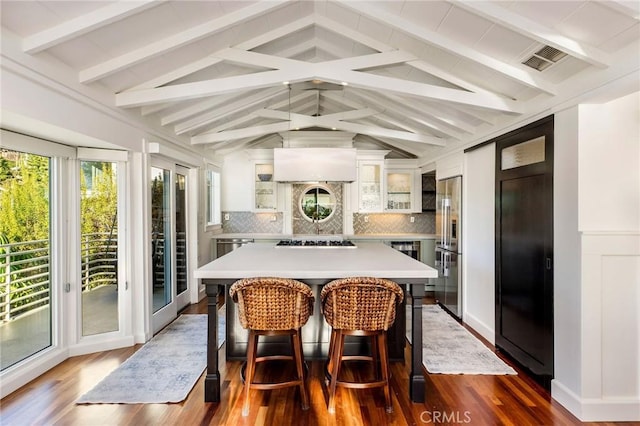 dining space featuring dark wood-style floors, visible vents, and lofted ceiling with beams