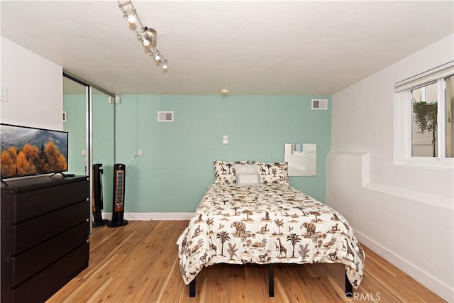 bedroom featuring a closet, rail lighting, and light hardwood / wood-style flooring