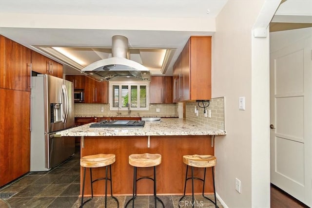 kitchen with tasteful backsplash, appliances with stainless steel finishes, a kitchen bar, and kitchen peninsula