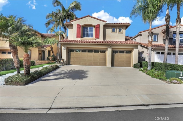 mediterranean / spanish house featuring a garage, concrete driveway, a tile roof, and stucco siding