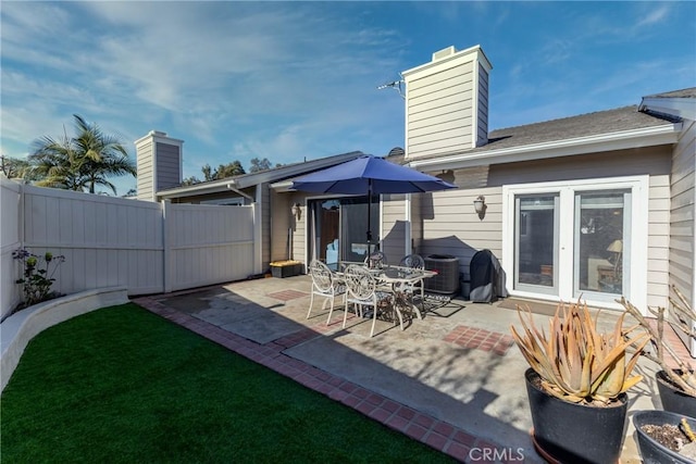 back of property with central air condition unit, a patio area, a chimney, and fence