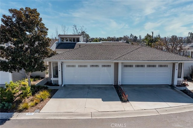 view of front of property with a garage, driveway, and roof with shingles