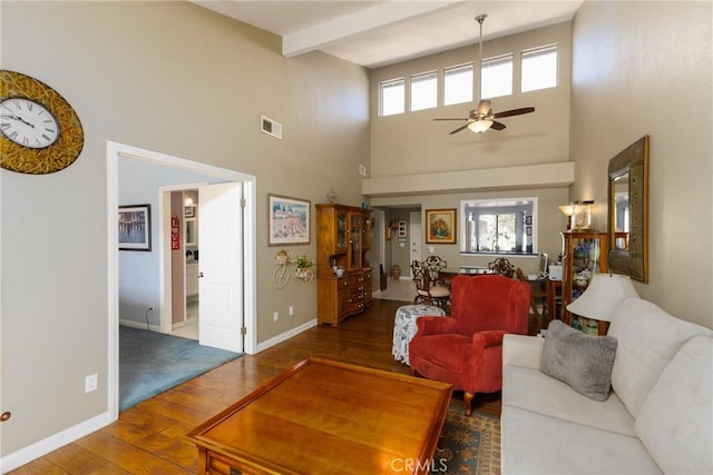 living room with beam ceiling, visible vents, ceiling fan, wood finished floors, and baseboards