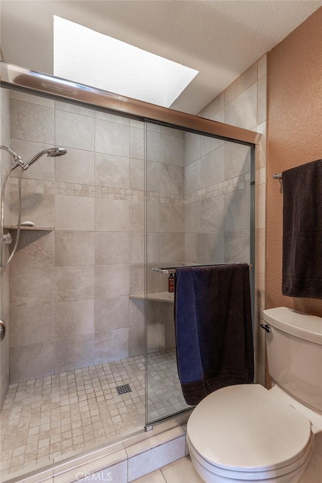 full bath with toilet, tile patterned flooring, a shower stall, and a textured ceiling