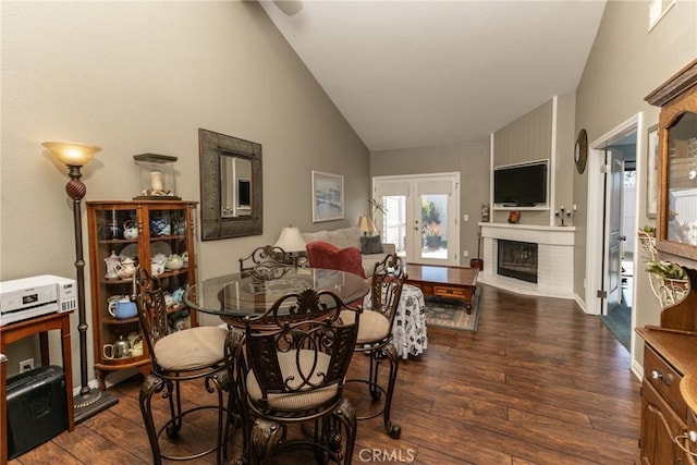 dining area with lofted ceiling, a fireplace, dark wood finished floors, and french doors