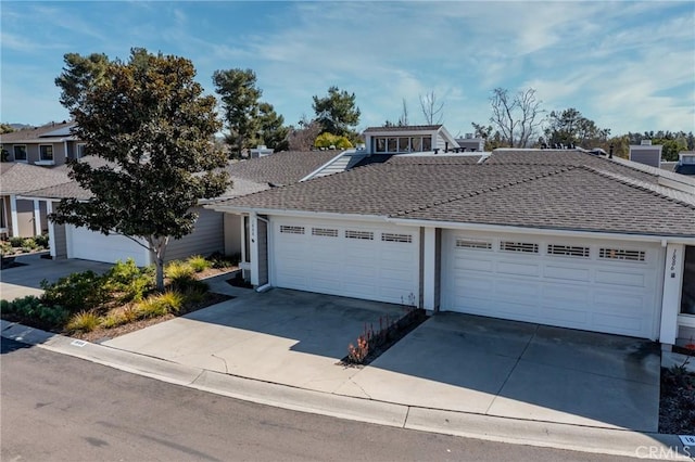 view of front facade featuring driveway, roof with shingles, and an attached garage