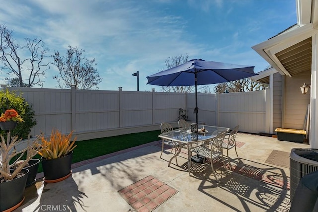 view of patio featuring central AC unit, outdoor dining area, and a fenced backyard