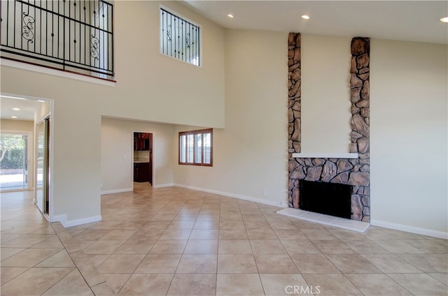 unfurnished living room featuring a fireplace, light tile patterned floors, plenty of natural light, and a high ceiling