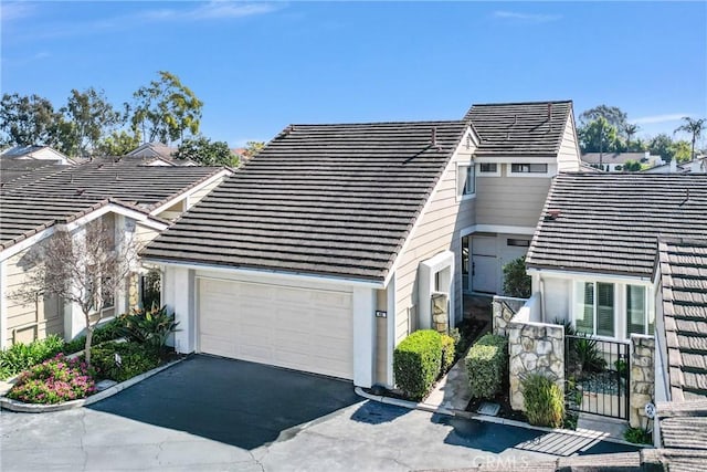 view of front of home with aphalt driveway, a tile roof, and an attached garage