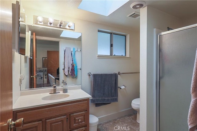 bathroom with a shower with door, vanity, tile patterned floors, and toilet