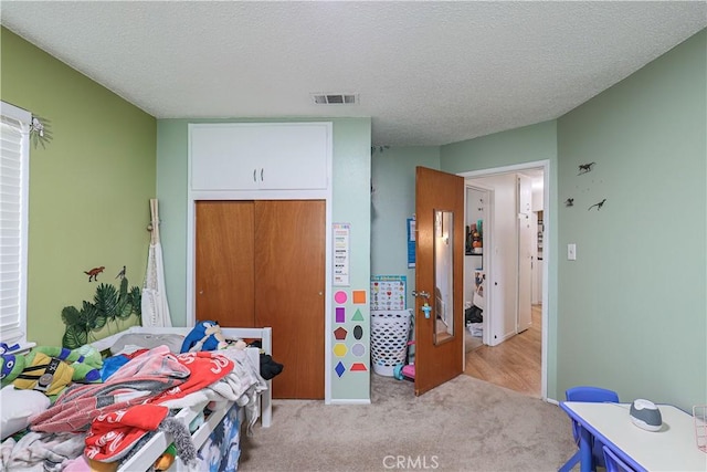 carpeted bedroom featuring a textured ceiling and a closet