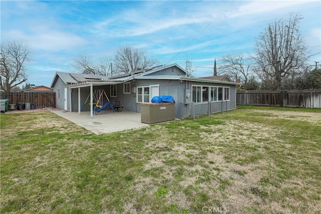 back of house featuring a yard, a patio area, and solar panels