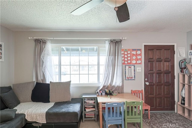 living room featuring ceiling fan, carpet flooring, and a textured ceiling