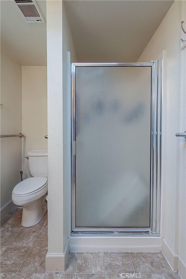 bathroom featuring toilet and a shower with shower door