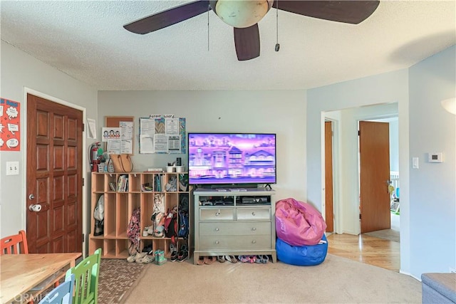 carpeted living room with ceiling fan and a textured ceiling