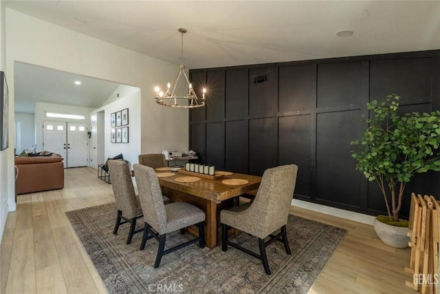 dining space with light hardwood / wood-style flooring, a chandelier, and vaulted ceiling