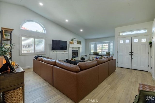 living room featuring high vaulted ceiling and light hardwood / wood-style floors